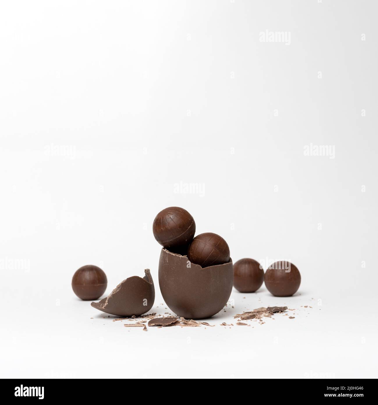 Chocolat craqué oeuf de pâques plein de chocolat petits bonbons ronds et chocolats sur fond blanc, espace de copie. Chocolat pour les enfants. Pâques co Banque D'Images