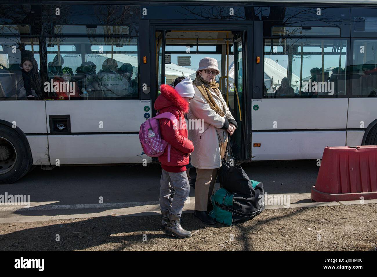 Une dame et sa petite-fille attendent de monter à bord d'un bus pour Suciava, la plus grande ville de la région de Siret. Environ 3 mille personnes arrivent quotidiennement à Siret, en Roumanie, pour se réfugier contre la violence causée par la guerre entre la Russie et l'Ukraine. Dans cette ville frontalière, un couloir d'aide humanitaire a été organisé entre diverses organisations civiles et étatiques. Les personnes qui fuient l'Ukraine sont principalement des femmes, des enfants et des adultes plus âgés. Lorsqu'ils franchissent la frontière, les gens reçoivent de l'aide médicale, psychologique, alimentaire, de transport et d'hébergement. Grâce à l'aide des bénévoles, ces personnes peuvent prendre une pause et gagner str Banque D'Images