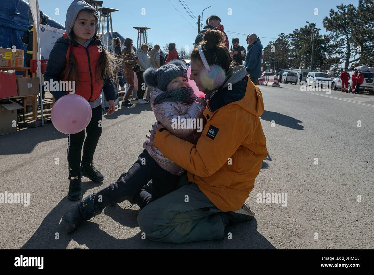 Magda, un volontaire humanitaire, hople et joue avec les enfants qui traversent la frontière avec leurs familles. Environ 3 mille personnes arrivent quotidiennement à Siret, en Roumanie, pour se réfugier contre la violence causée par la guerre entre la Russie et l'Ukraine. Dans cette ville frontalière, un couloir d'aide humanitaire a été organisé entre diverses organisations civiles et étatiques. Les personnes qui fuient l'Ukraine sont principalement des femmes, des enfants et des adultes plus âgés. Lorsqu'ils franchissent la frontière, les gens reçoivent de l'aide médicale, psychologique, alimentaire, de transport et d'hébergement. Grâce à l'aide des bénévoles, ces personnes peuvent prendre une pause et Banque D'Images