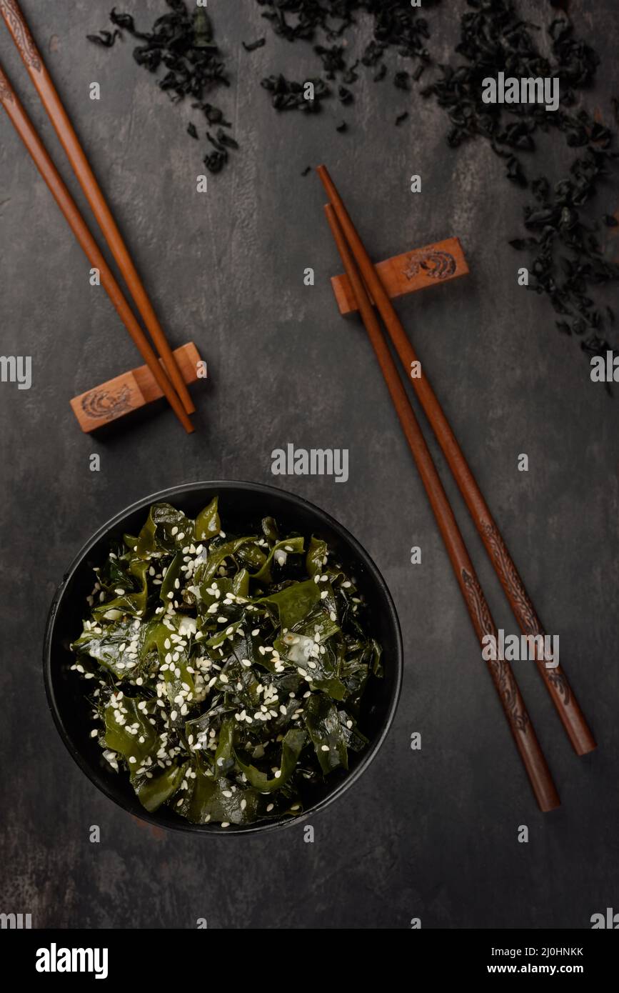 Salade d'algues wakame. Bol et bâtonnets de bambou. Cuisine orientale. Vue de dessus. Banque D'Images