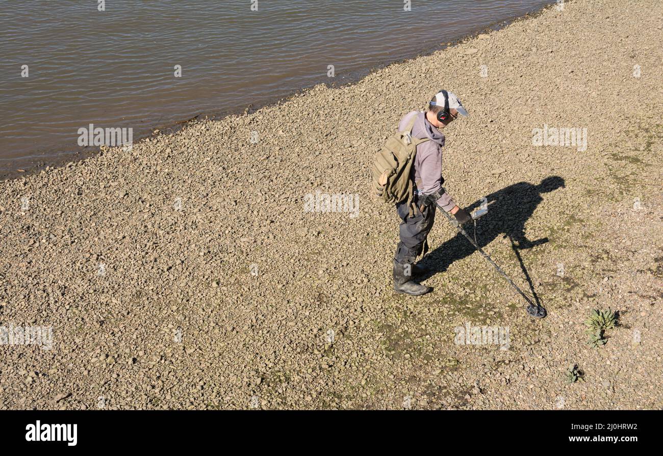 Un seul homme blanc détectant du métal sur la rive en gravier de la Tamise à Londres, Angleterre, Royaume-Uni Banque D'Images