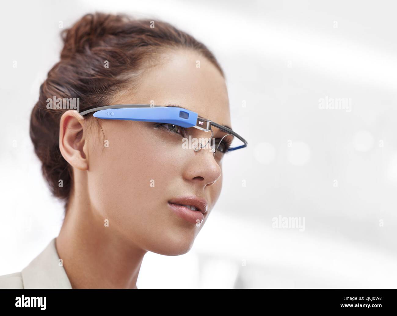 Photo courte d'une jeune femme attrayante portant des lunettes avec accès à Internet. Le ou les produits commerciaux ou les dessins affichés sur cette image représentent Banque D'Images