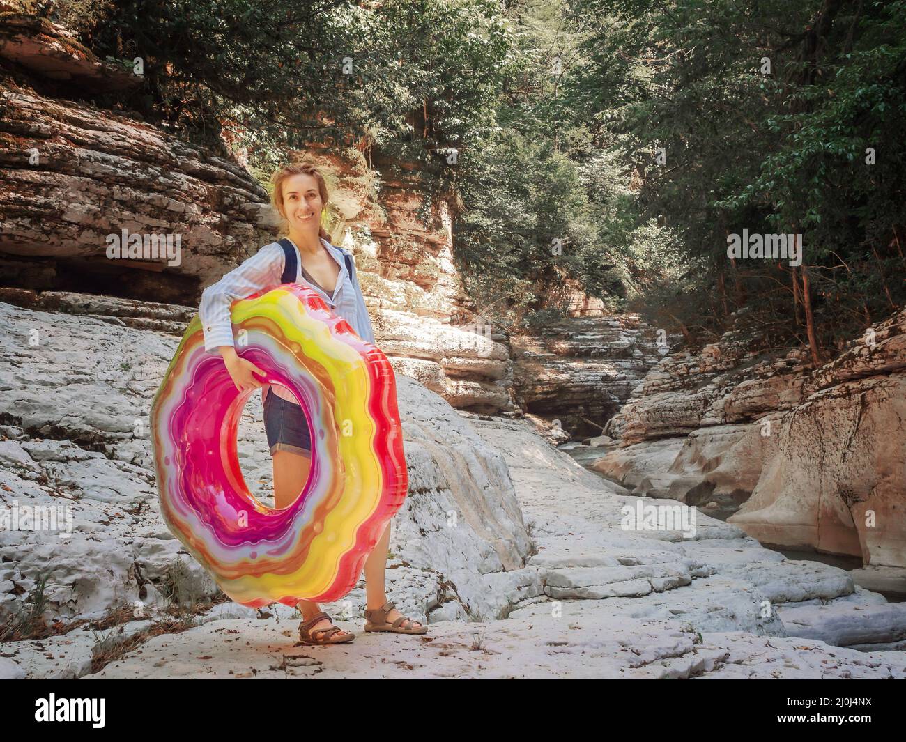 Une fille souriante avec un anneau gonflable lumineux se dresse parmi les canyons de la réserve naturelle de Khosta Banque D'Images