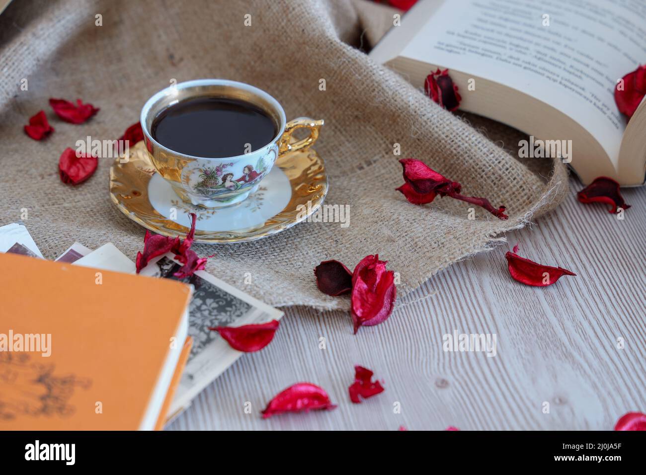 Café Turkısh dans une tasse classique, fond en bois avec des pétales de rose romantiques, livre sur l'amour parmi les anciennes photos d'époque, décorer de couleur beige. Banque D'Images
