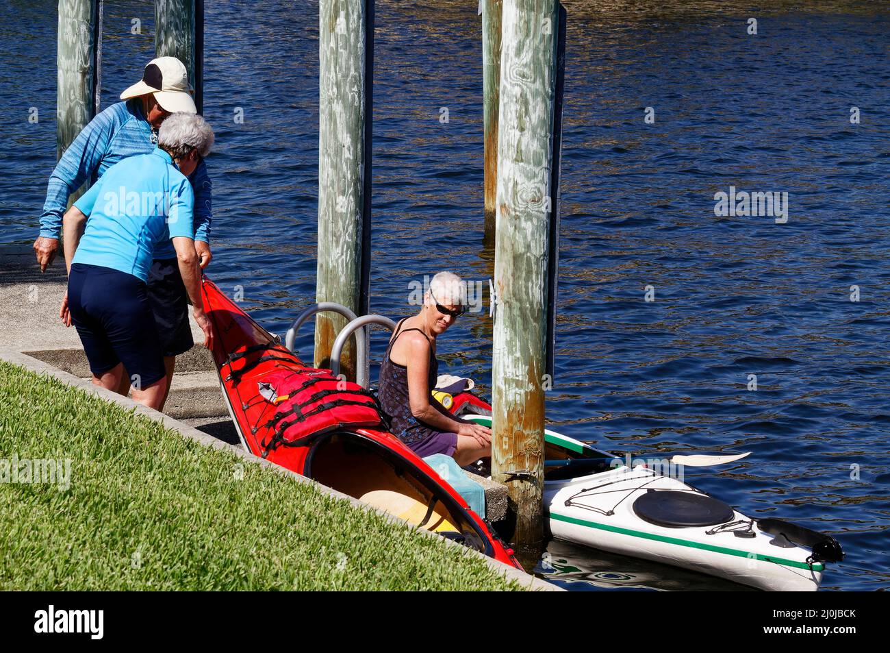 3 personnes mettant des kayaks dans l'eau, quai, sport, loisirs, amusement, Exercice, Floride, Punta Gorda, FL, MR Banque D'Images