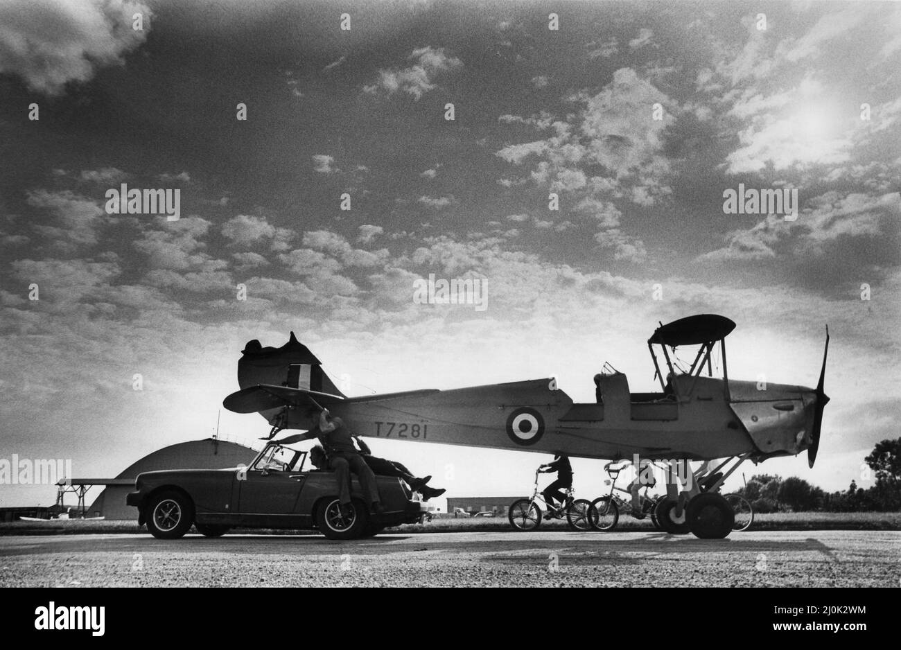 Le de Havilland Tiger Moth, basé à l'aéroport de Sunderland, qui a développé des problèmes de moteur lors du décollage. Le pilote Steve Marples a glissé l'avion sur un terrain près de l'étang de Barmston, il a fait une touche parfaite vers le bas, mais les roues se sont emmêlées dans le maïs, provoquant le retournement de l'avion. M. Marples et son copropriétaire et passager Alan Jackson sont sortis sans douleur, l'avion est ici remorqué par une VOITURE DE sport MG Midget. 30/06/1982 Banque D'Images