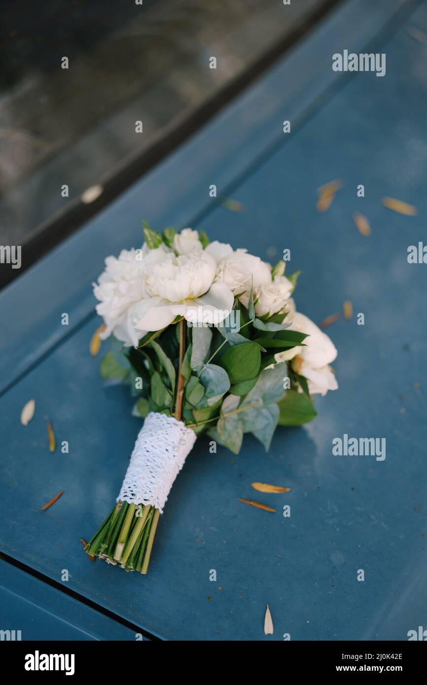 Bouquet de mariée de pivoines blanches, roses, branches d'eucalyptus et ruban de dentelle sur la capuche de la voiture Banque D'Images