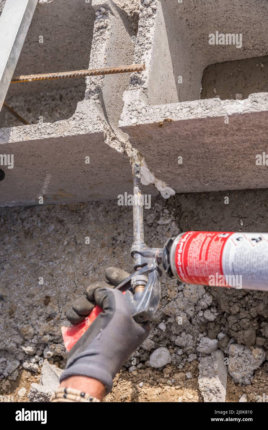 Un travailleur qualifié travaille sur le chantier de construction avec de la mousse de remplissage - industrie de la construction Banque D'Images