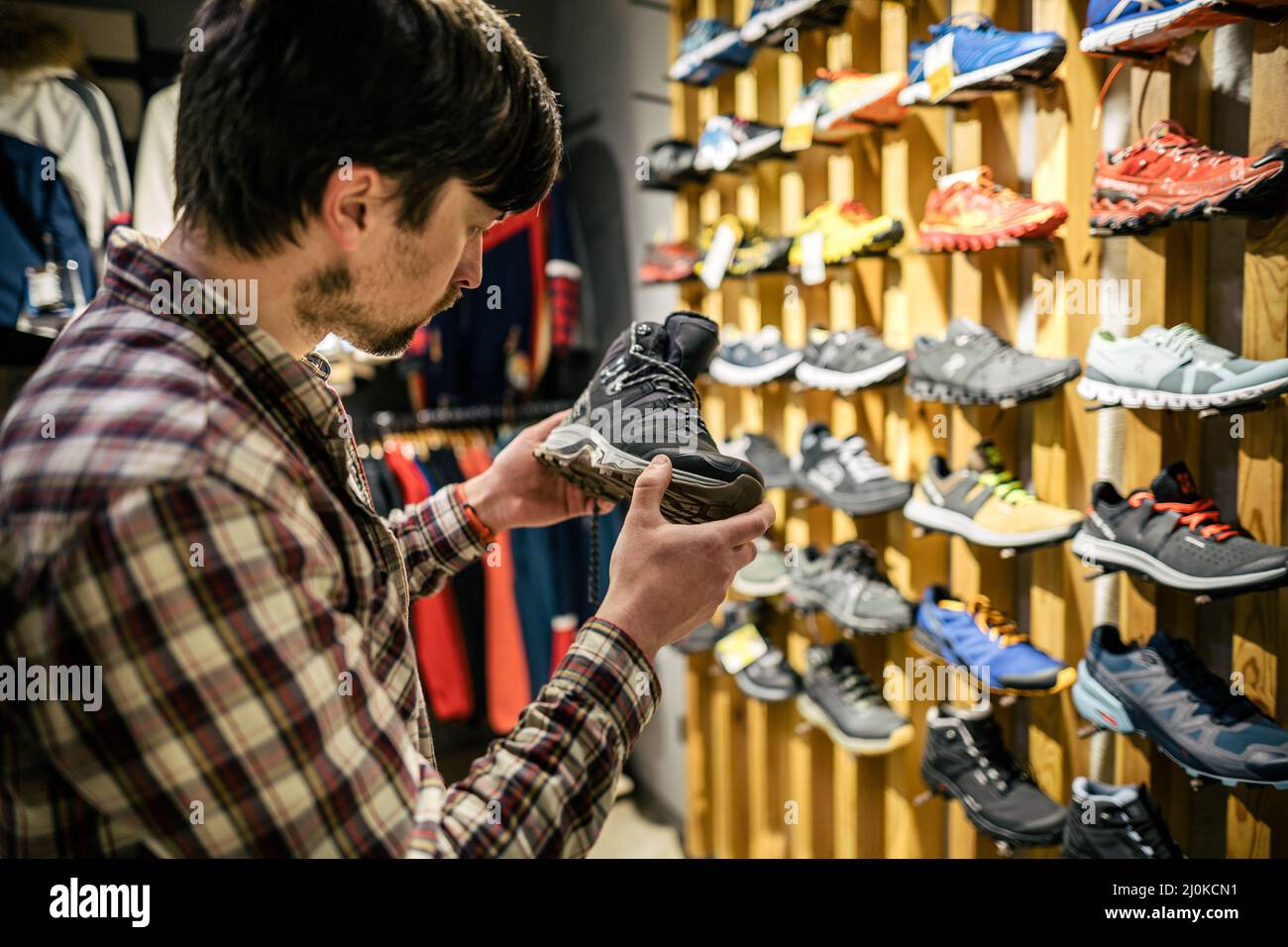 Homme magasiner dans un magasin en plein air. Homme achetant des bottes de montagne. Sélection de chaussures de randonnée pour les amateurs de shopping dans les magasins de sport. Achat client de Banque D'Images
