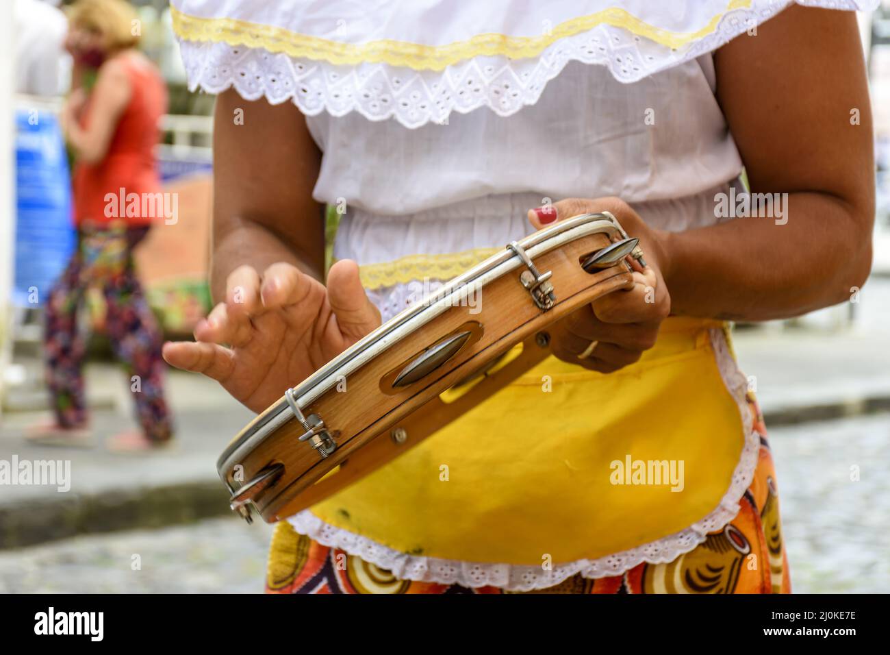 Femme en vêtements ethniques colorés jouant du tambourin Banque D'Images