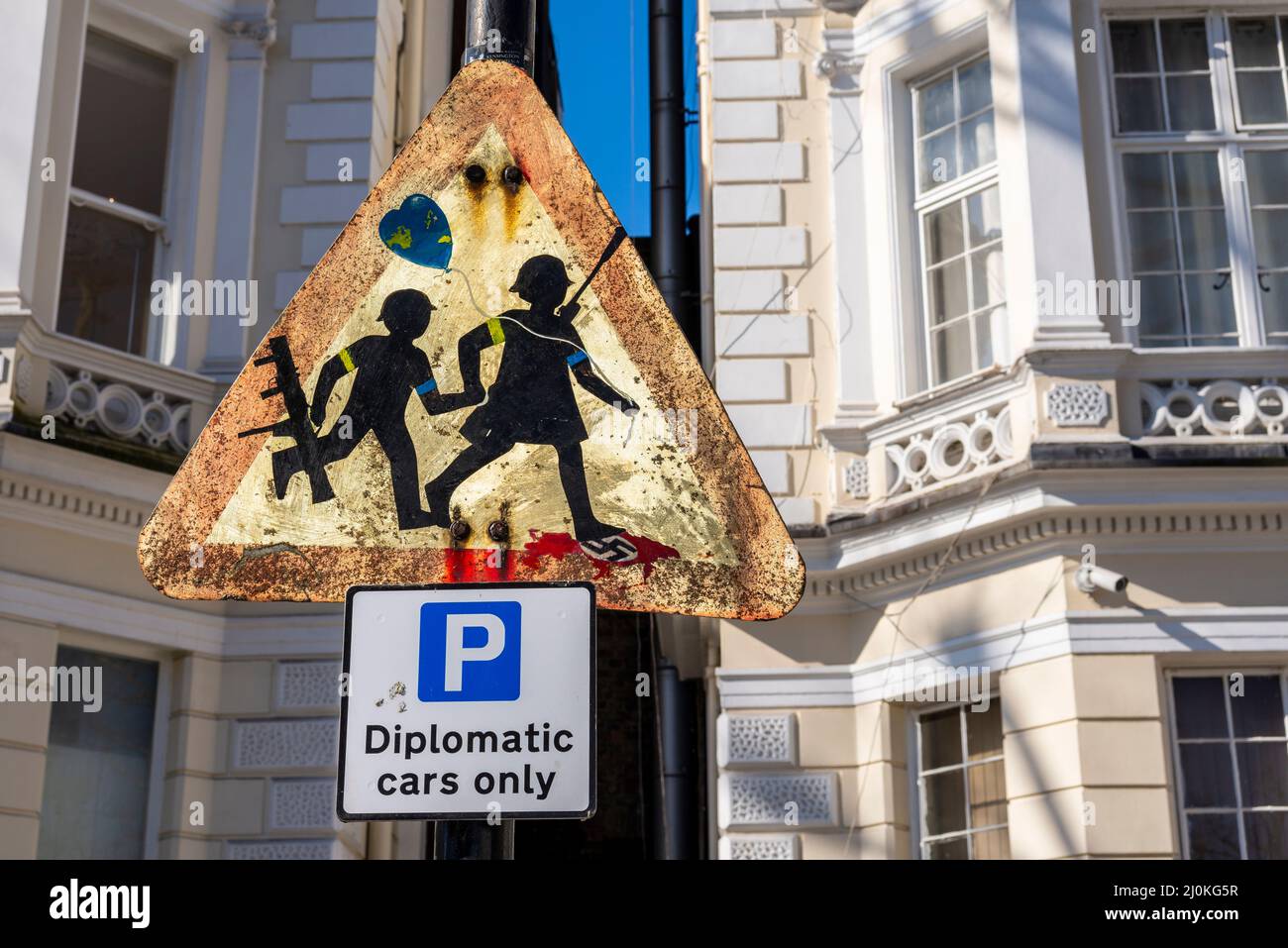 Attention aux enfants, le triangle de signalisation routière a été modifié pour créer des soldats ukrainiens qui marchaient au-dessus du drapeau de la croix gammée nazie. Près de l'ambassade d'Ukraine, Londres Banque D'Images