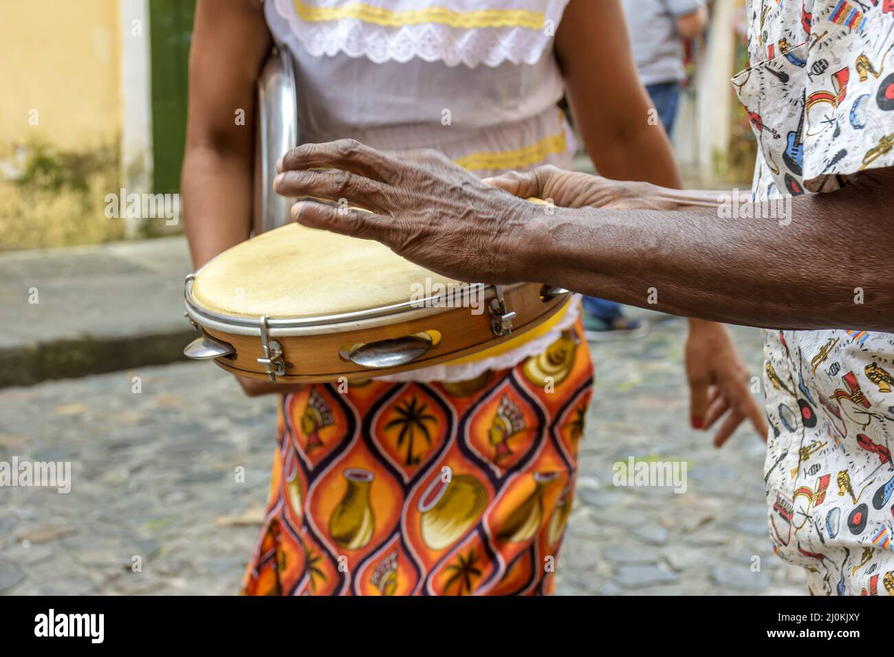 Le joueur de tambourine a les mains d'une femme en vêtements typiques dansant en arrière-plan Banque D'Images