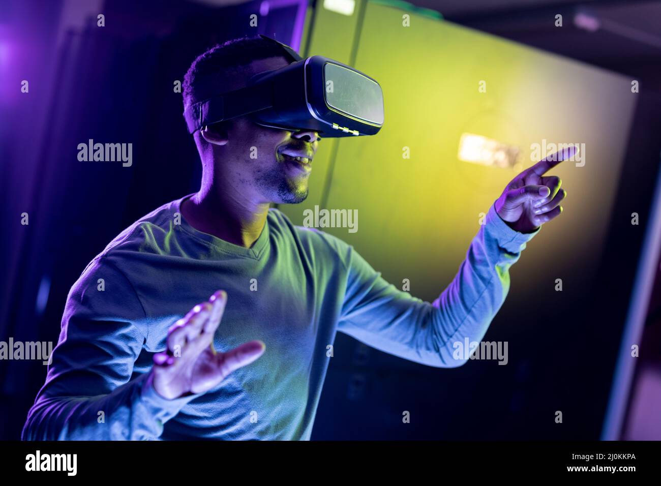 Un technicien informatique afro-américain portant un casque vr et travaillant dans une salle de serveurs Banque D'Images