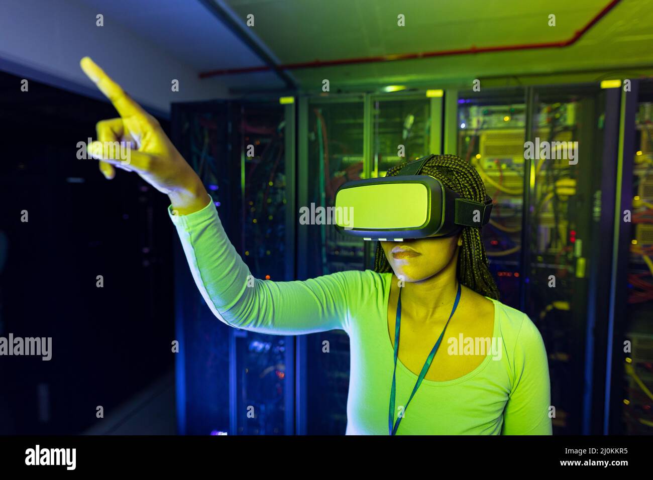 Une technicienne informatique afro-américaine portant un casque vr et travaillant dans une salle de serveurs Banque D'Images