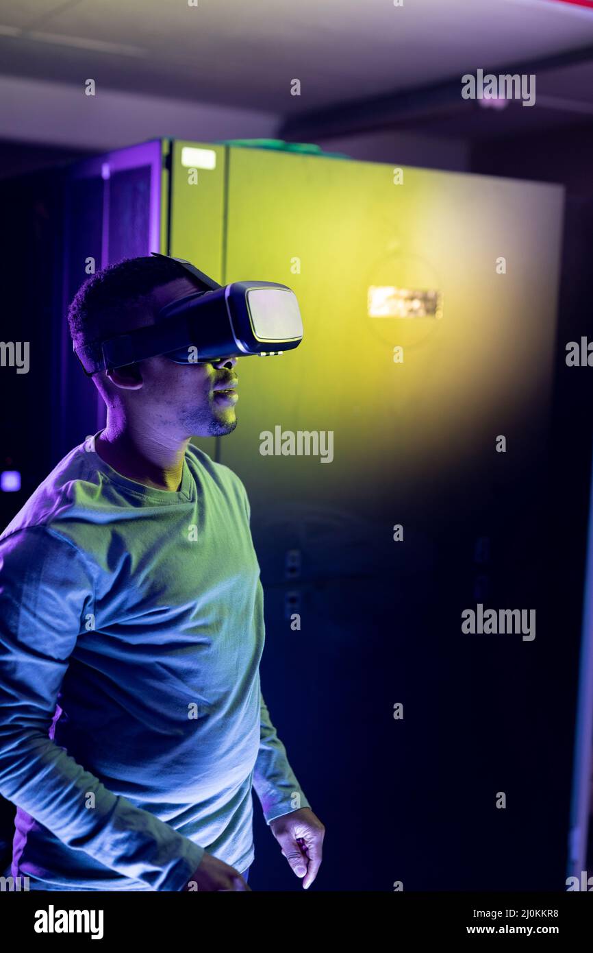 Un technicien informatique afro-américain portant un casque vr et travaillant dans une salle de serveurs Banque D'Images