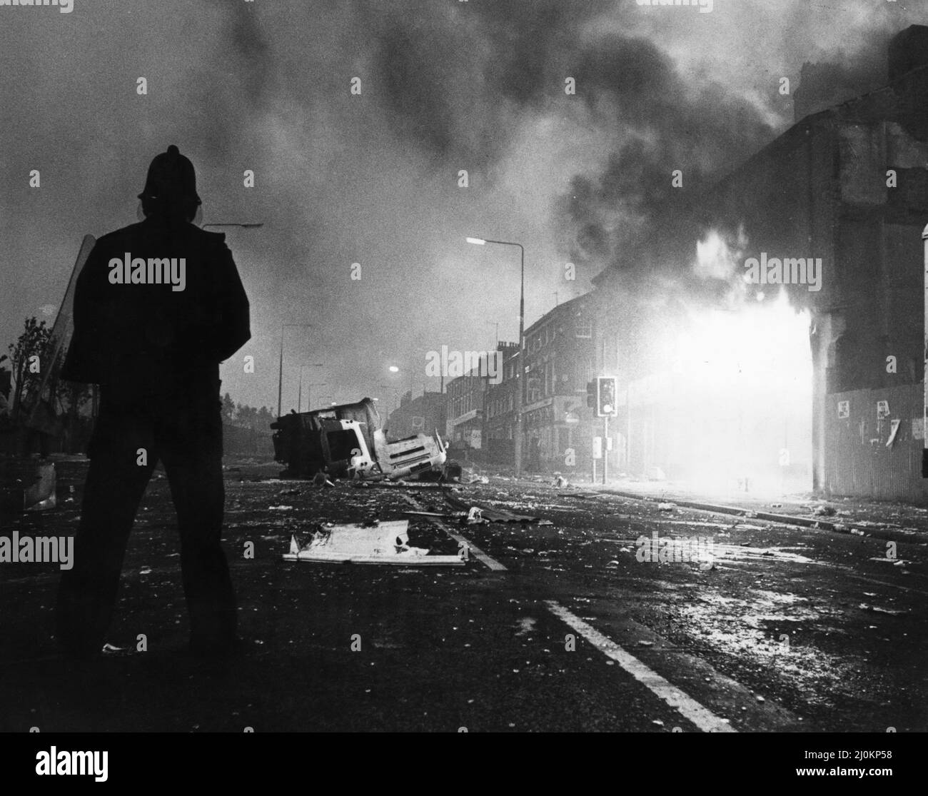 Toxteth Riot 5th juillet 1981a policier dans des stands de matériel antiémeute parmi les magasins de verre brisé et en feu de Park Road les émeutes ont été déclenchée à la suite de l'interception par la police des motocyclistes Leroy Cooper dans la rue Selbourne. Une foule s'est rassemblée, les noms se sont multipliés par des plaisanteries et en quelques minutes, il y avait une fracture à grande échelle qui a vu trois policiers blesser et un jeune homme local, arrêté pour voies de fait. Cela ne s'est pas arrêté là. La police a monté des patrouilles supplémentaires dans la région et tôt le soir suivant, le 4 juillet, ils ont été attaqués par une foule armée de briques et de bombes à essence. Le fu Banque D'Images