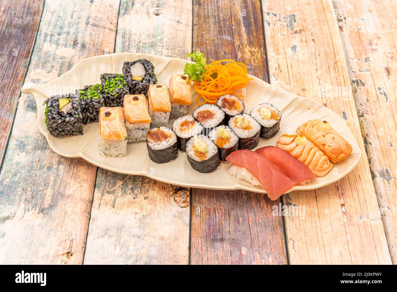 Plateau à sushi assorti avec morceaux de nigiri de saumon en lambé, thon rouge, maquis avec sauces et uramaki avec riz noir et mangue Banque D'Images