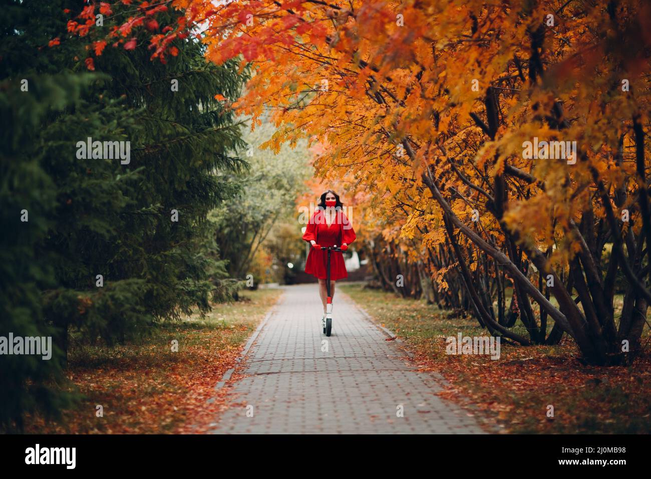 Jeune femme à cheval électrique dans la ville d'automne Banque D'Images