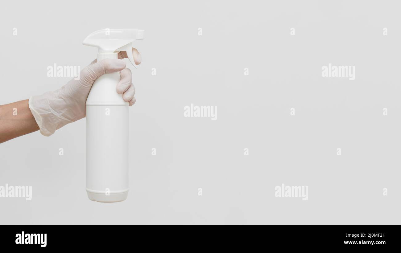 Main avec un gant contenant la solution de nettoyage dans un flacon avec espace de copie Banque D'Images