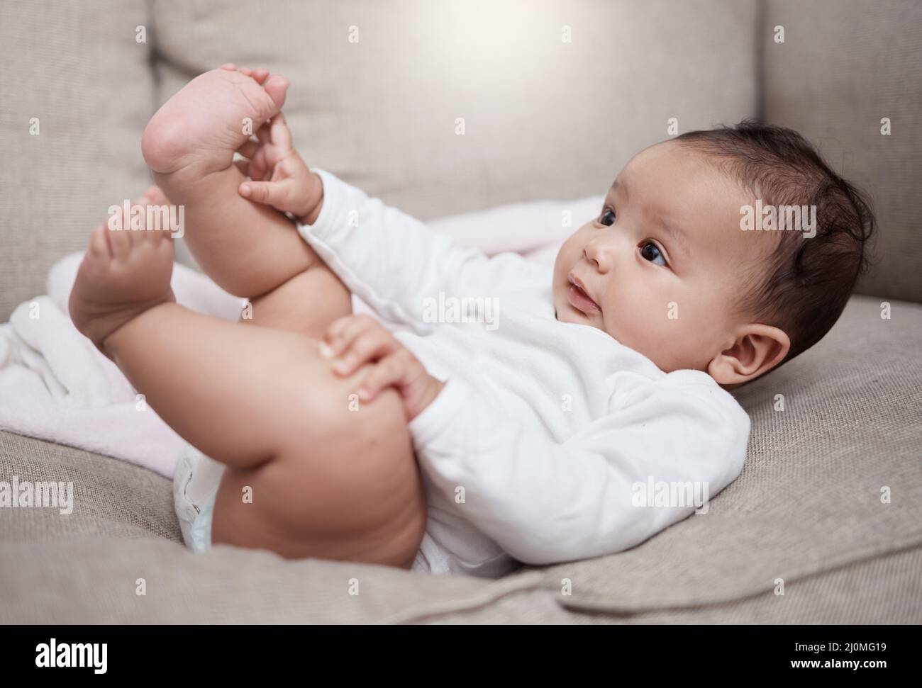 HES juste curieux de tout. Prise de vue d'un adorable bébé allongé sur un canapé à la maison. Banque D'Images