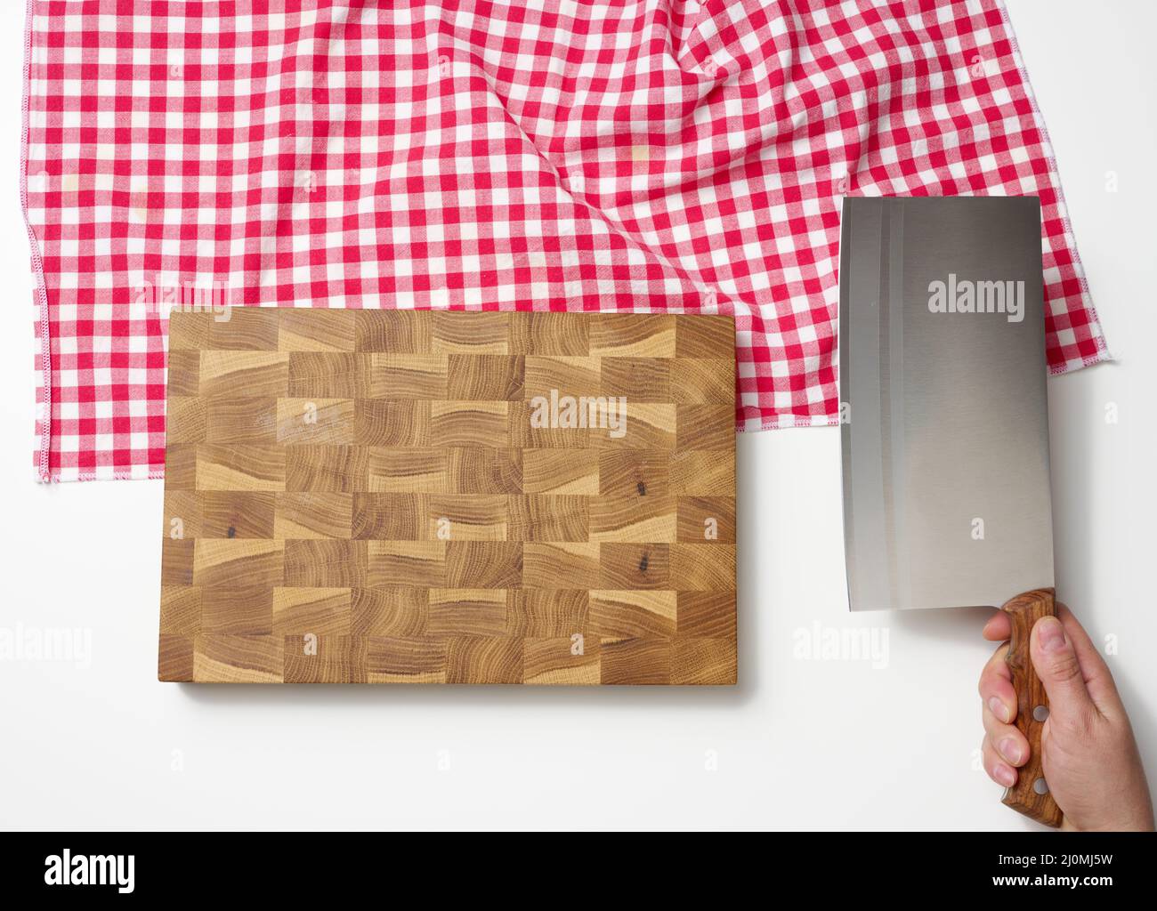 Planche à découper en bois vide et main féminine tenant un grand couteau de cuisine aiguisé pour couper de la viande sur fond blanc Banque D'Images