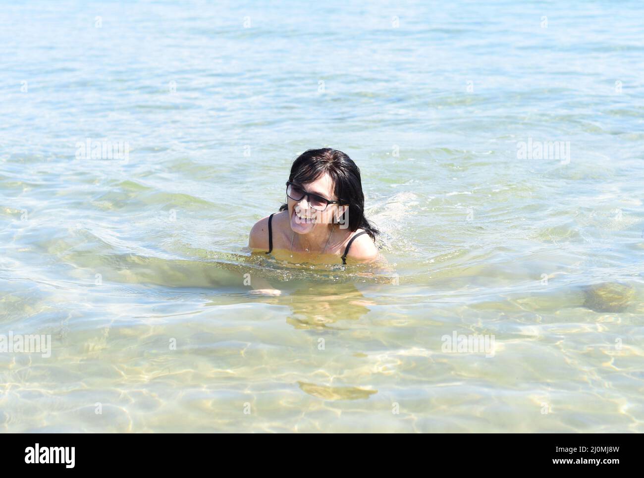 Femme russe de 45 ans en maillot de bain riant et se tenant dans la mer japonaise Banque D'Images