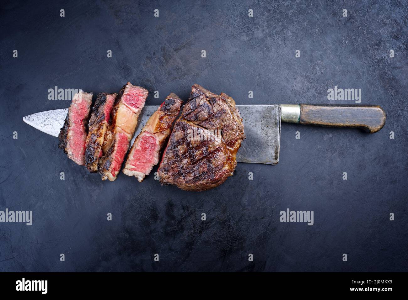 Grillades traditionnelles de bœuf Wagyu vieilli sec tranché et servi comme vue de dessus sur un grand couteau rustique sur un tableau noir W Banque D'Images