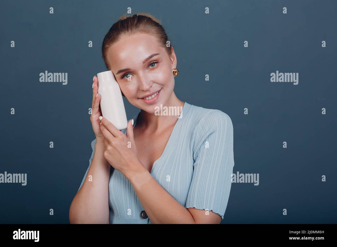Jolie jeune femme tient le flacon avec l'espace vide.Shampooing et après-shampooing. Banque D'Images