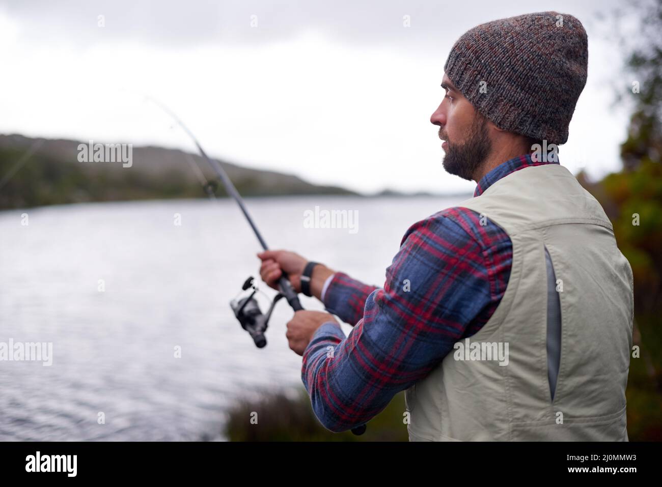 Attendre que le poisson mord. Photo d'un bel homme pêchant dans un lac naturel. Banque D'Images