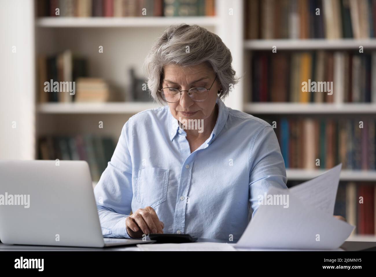 Une femme plus âgée s'assoit à la table calcule le résumé du paiement mensuel Banque D'Images