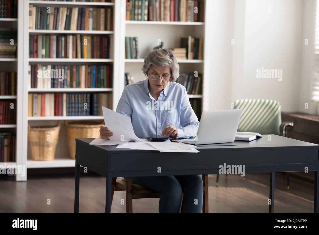 Femme mûre qui trie les factures, occupée dans la gestion des finances Banque D'Images