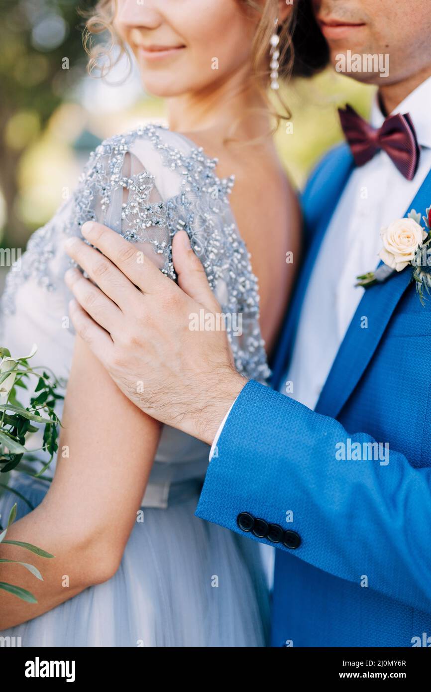 Kotor, Montenegro - 08.06.17: Marié dans un costume bleu hale la mariée avec un bouquet de fleurs par les épaules.Gros plan Banque D'Images