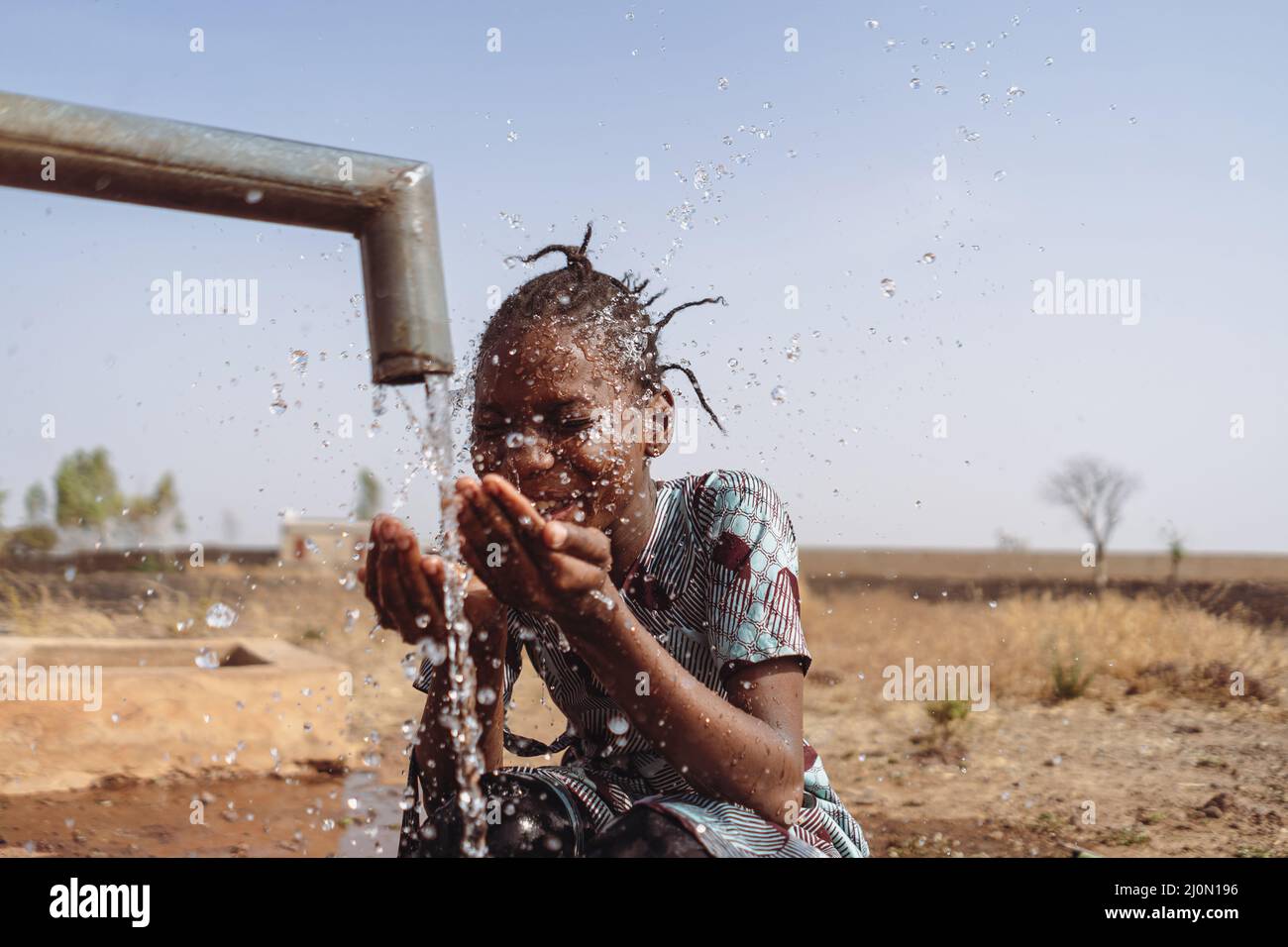 Poignée d'eau, poignée de joie pour cette jeune fille africaine. Banque D'Images