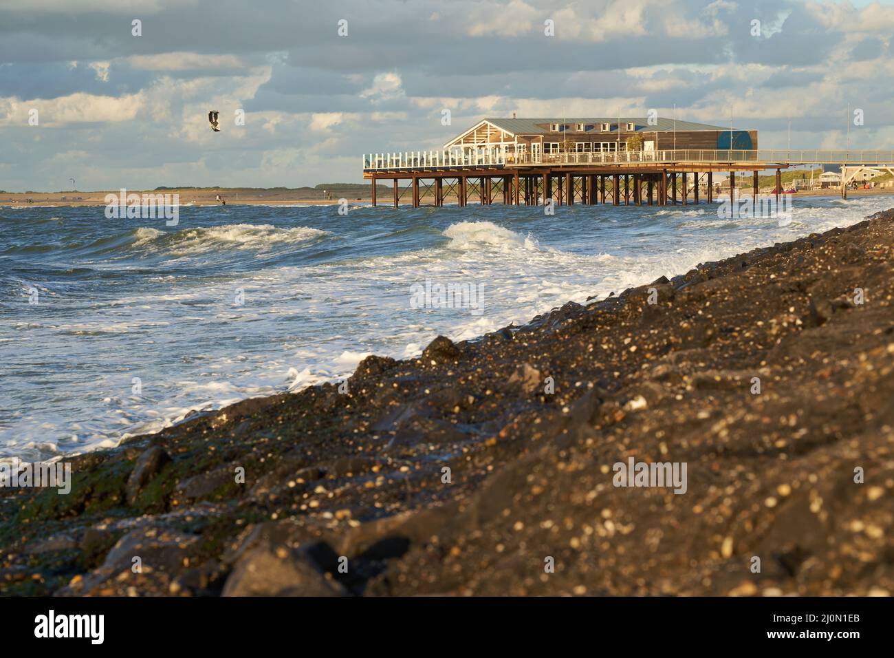 Zeeland, Hollande - 27 septembre 2021 : restaurant de plage sur pilotis dans la soirée sur la mer du Nord. Bâtiment au-dessus de l'eau sur le barrage pierreux. Sp. Eau Banque D'Images