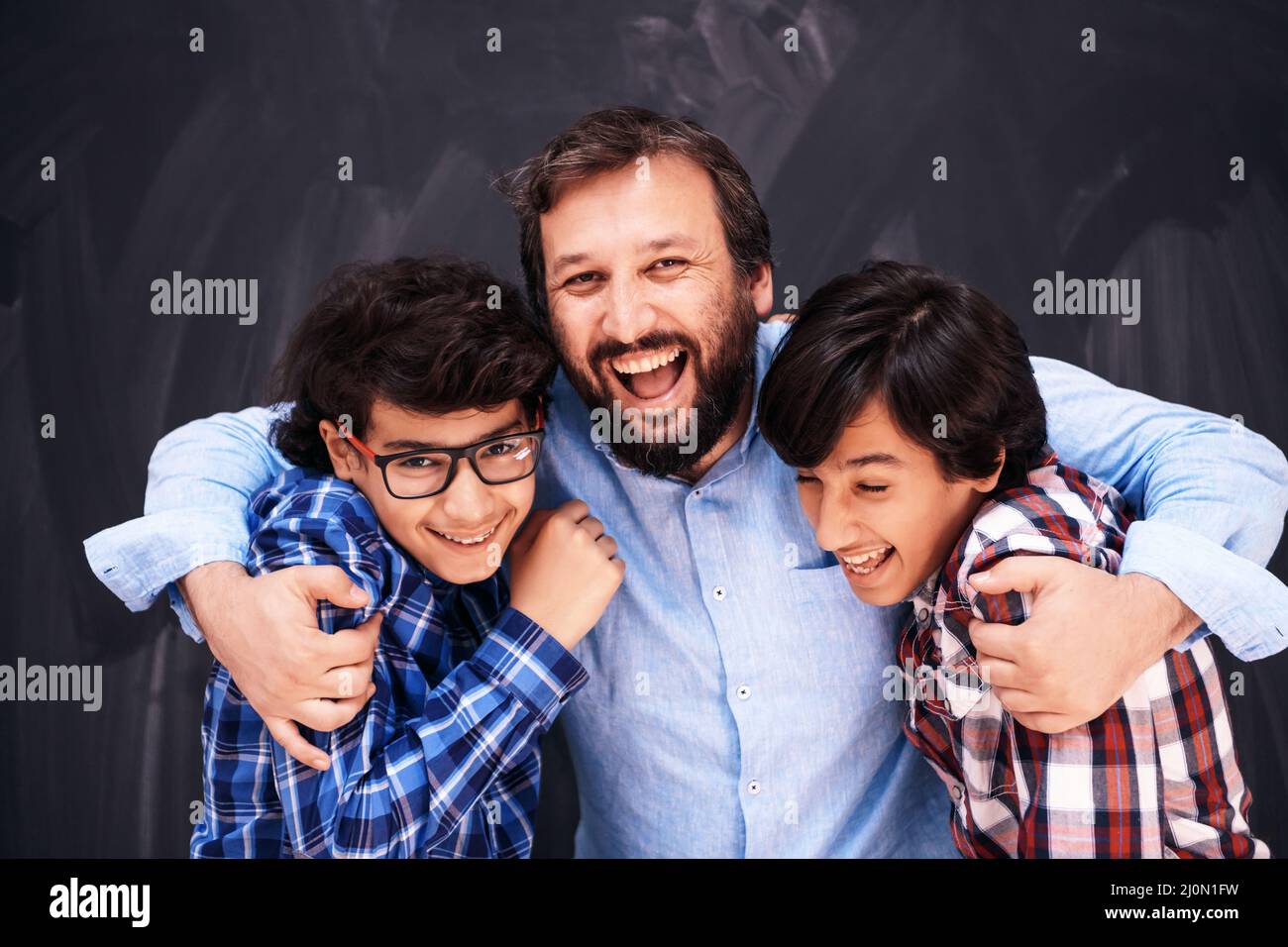 Un père heureux embrassant des fils des moments inoubliables de joie de famille dans la famille arabe moyen-orientale de race mixte Banque D'Images