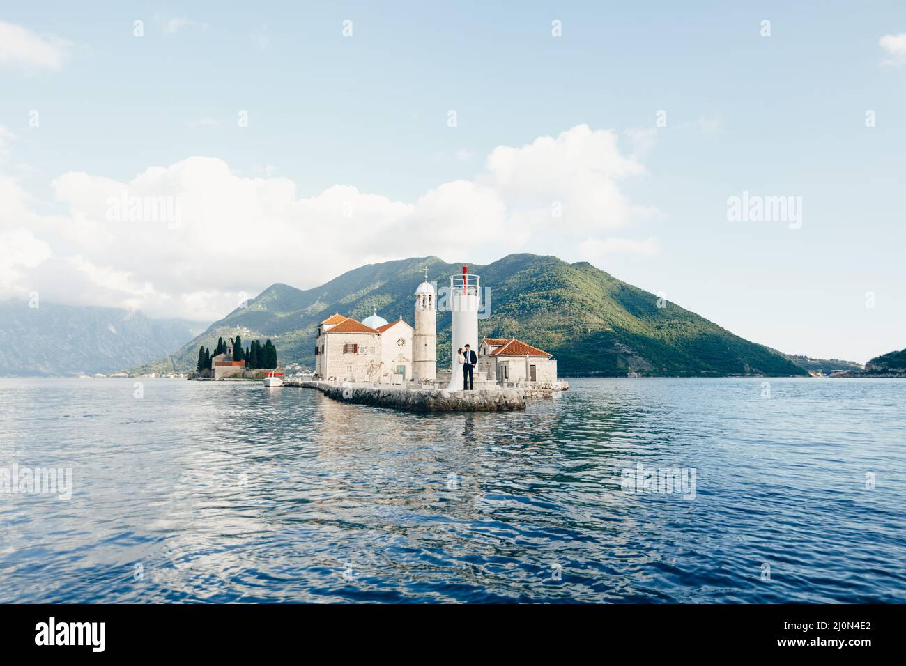 Les jeunes mariés s'embrassent sur l'île de Gospa od Skrpjela en face de l'église dans la baie de Kotor Banque D'Images