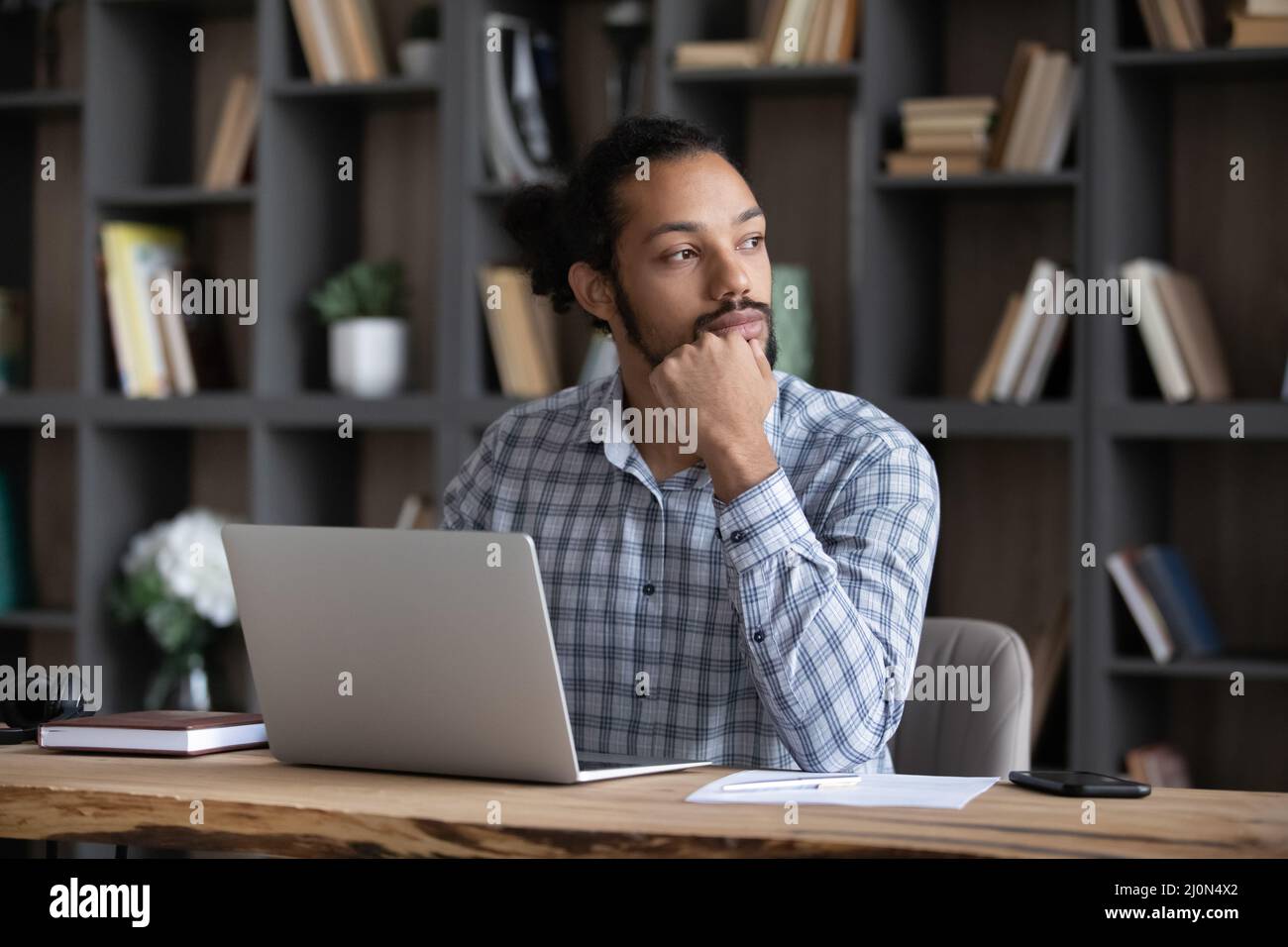 Un jeune entrepreneur africain sérieux et réfléchi travaillant sur un ordinateur portable Banque D'Images