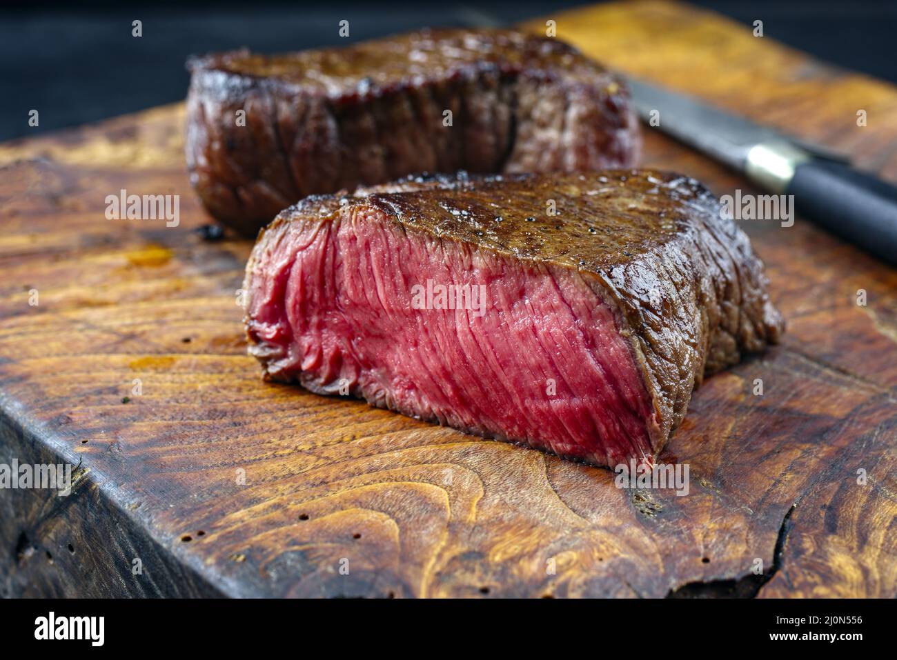 Steak traditionnel de bœuf haché sec frit servi en gros plan dans un vieux panneau rustique en bois Banque D'Images