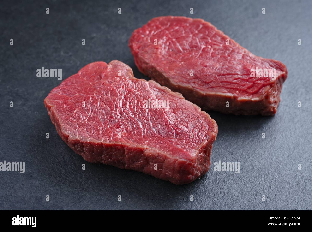 Steaks de bosse de bœuf de bison vieilli et sec crus offerts en gros plan sur fond noir avec espace de copie Banque D'Images