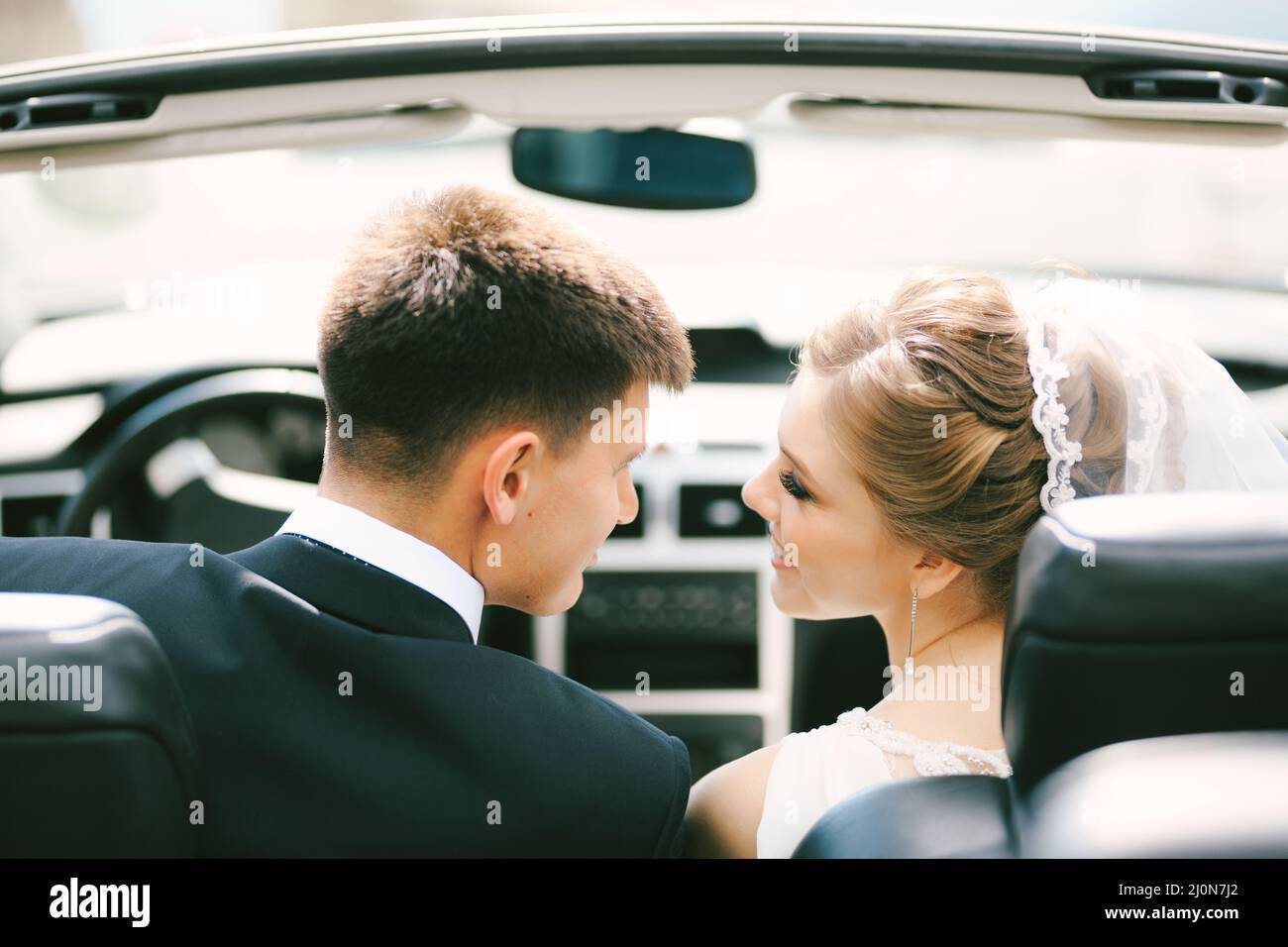 Les jeunes mariés se sourient les uns les autres tout en étant assis dans un cabriolet.Gros plan Banque D'Images
