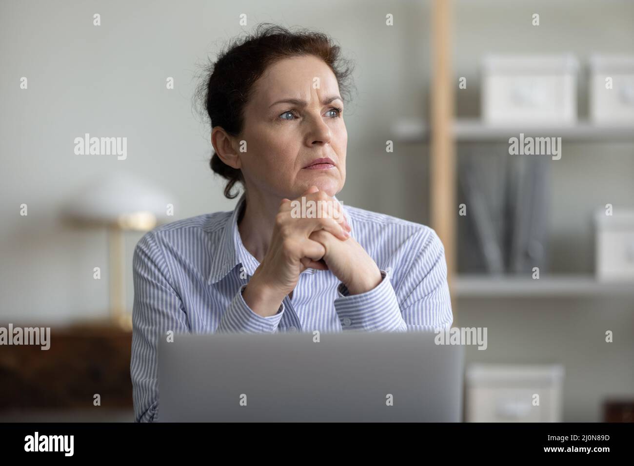 Inquiet femme d'affaires frustrée et mûre assise sur un ordinateur portable au bureau Banque D'Images