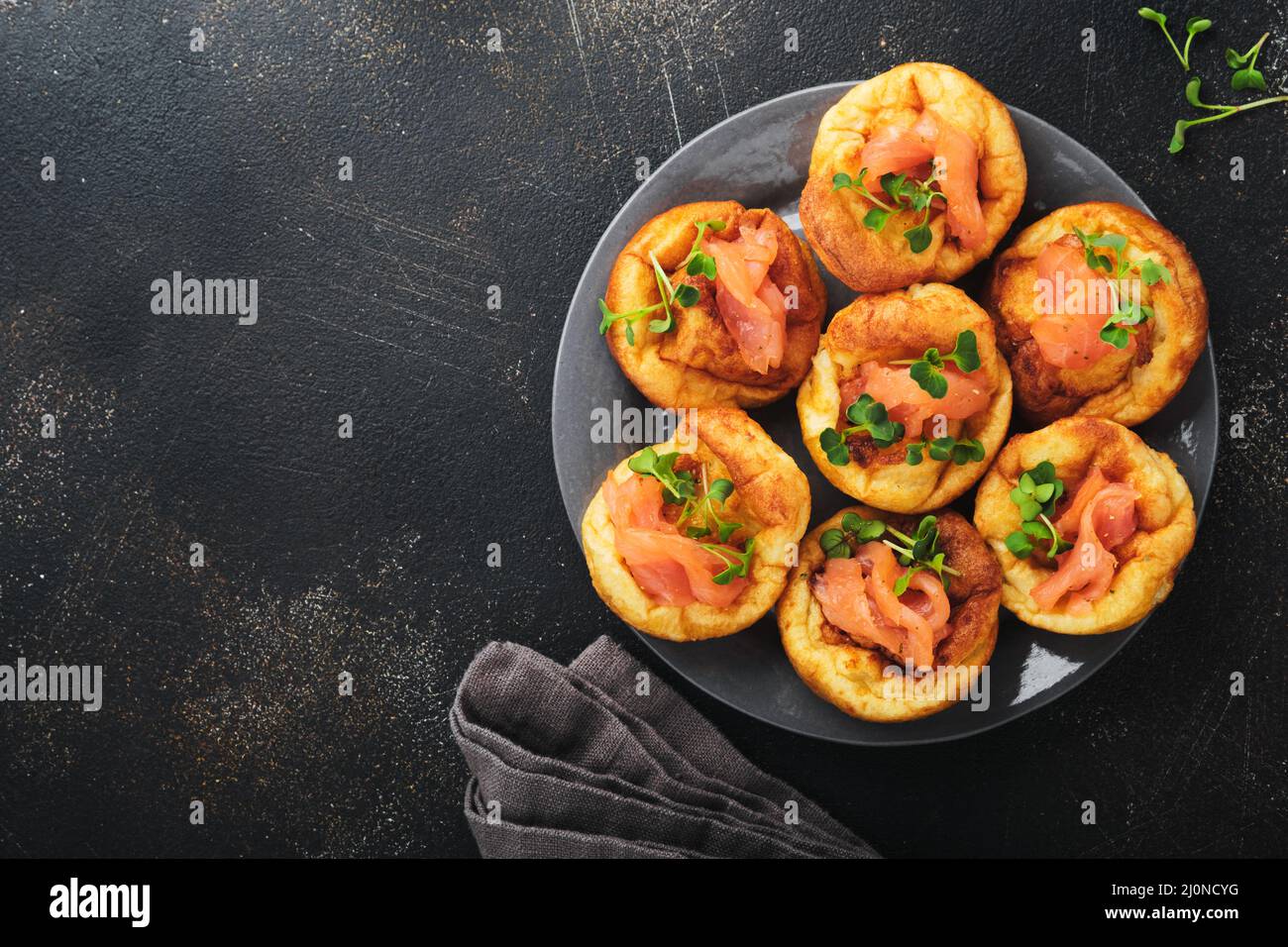 Yorkshire pudding. Traditionnel Yorkshire pudding avec saumon et radis microverts accompagnement sur plaque gris foncé et table de fond sombre. À Banque D'Images