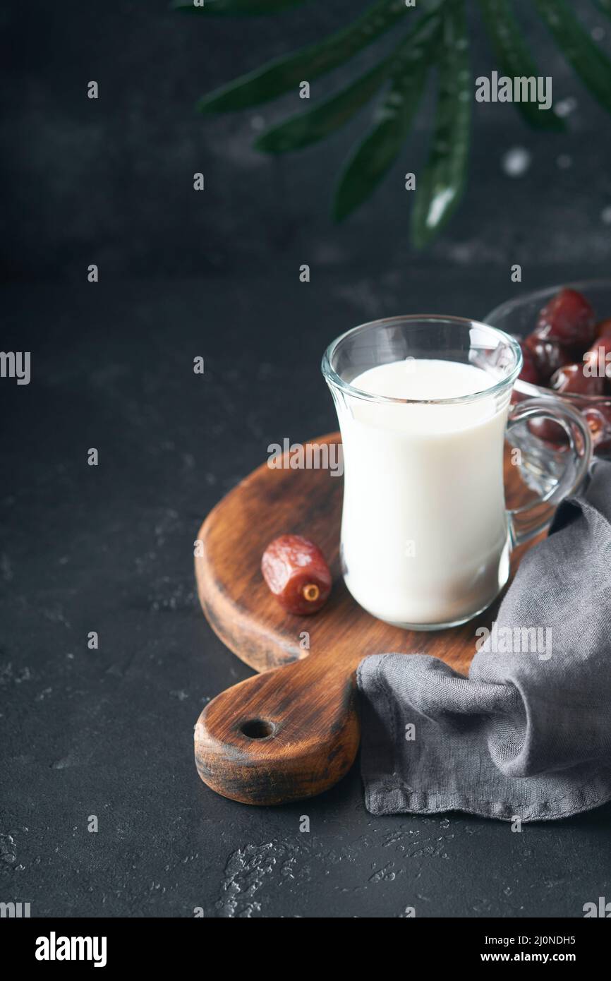 Plats et boissons du Kareem de Ramadan. Assiette de dattes, verre de lait et branche de palmier dattier sur fond noir. Un style de vie musulman juste. Plats végétariens. S Banque D'Images
