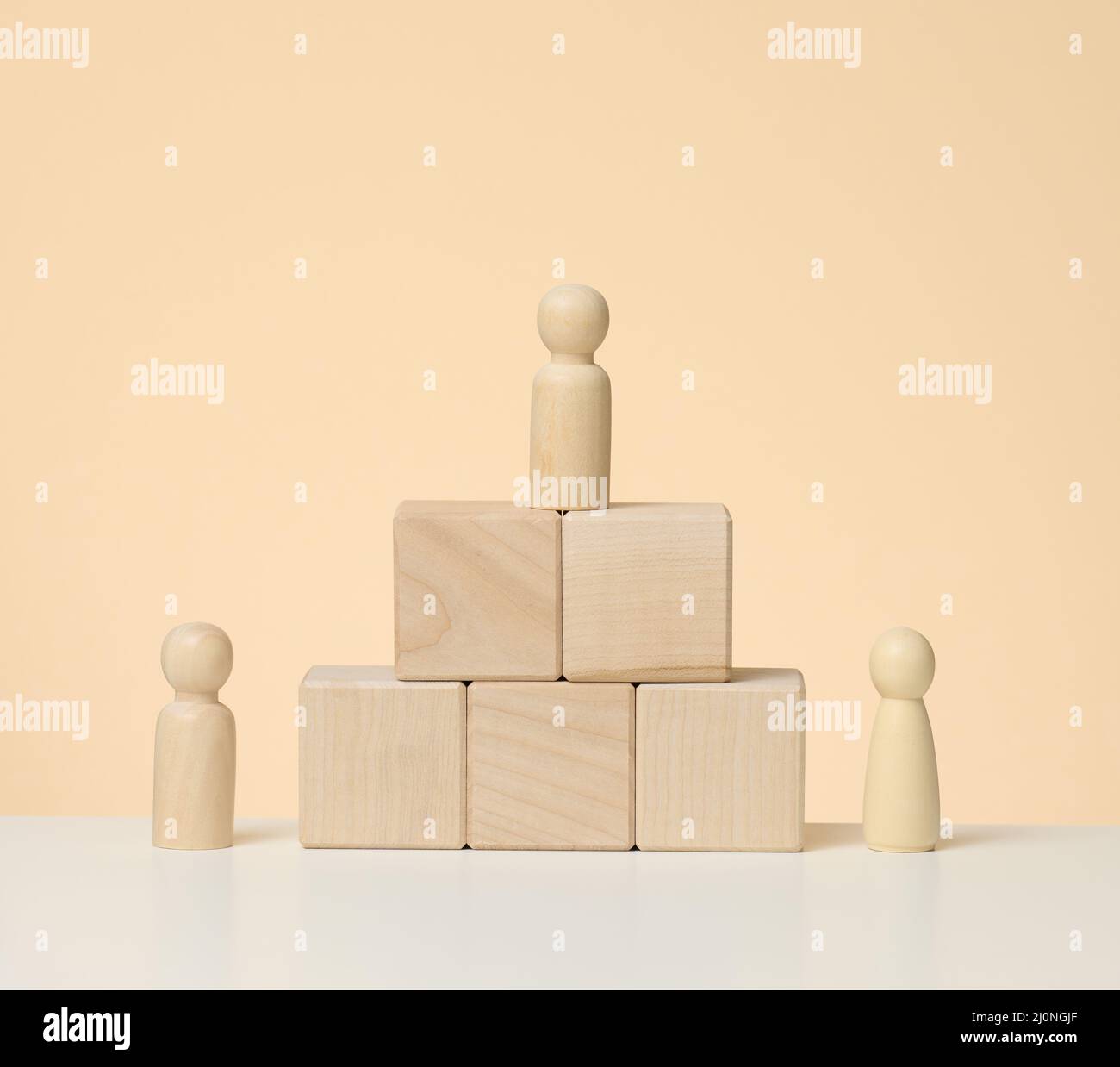 Les figures en bois des hommes se tiennent sur un piédestal de leurs cubes. Le concept de rivalité dans le sport, les affaires et la vie Banque D'Images