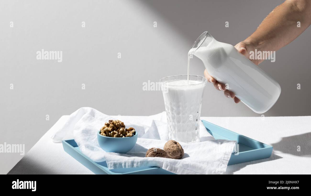 Personne versant le lait plein verre avec plateau à noix . Haute qualité et résolution magnifique concept de photo Banque D'Images