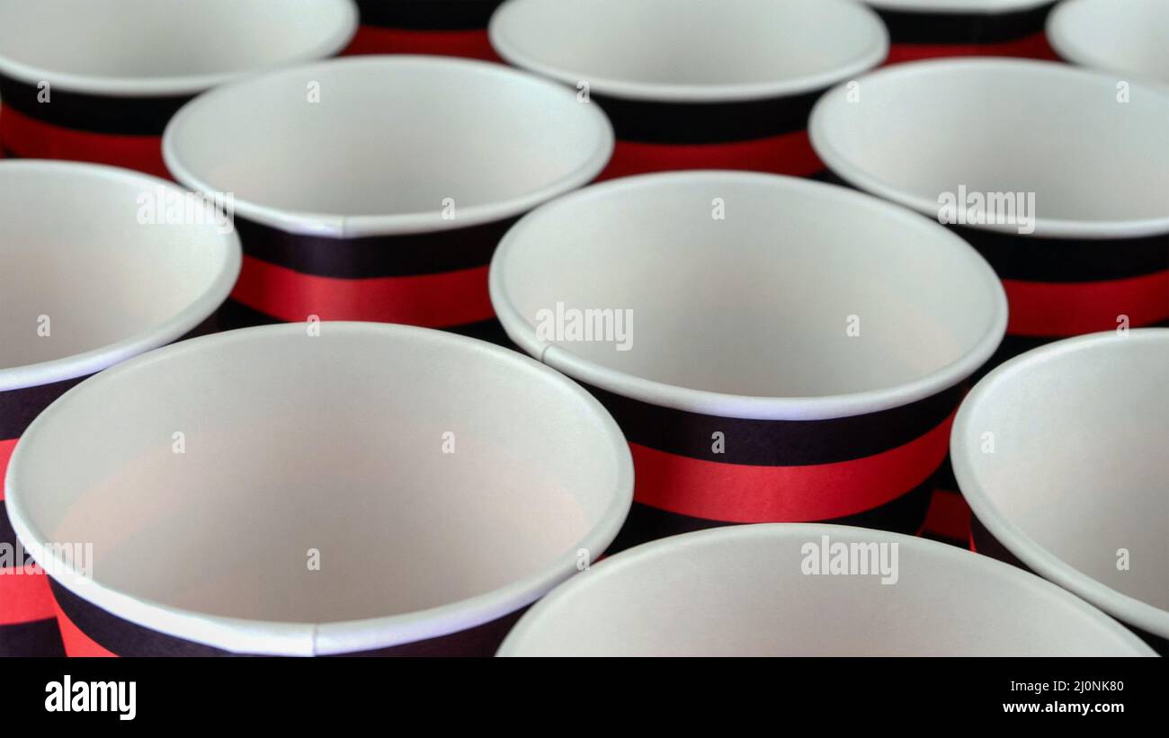 Tasse en papier écologique jetable rouge et noir pour café ou boisson chaude sur fond sombre. Mise au point sélective. Gros plan. Banque D'Images