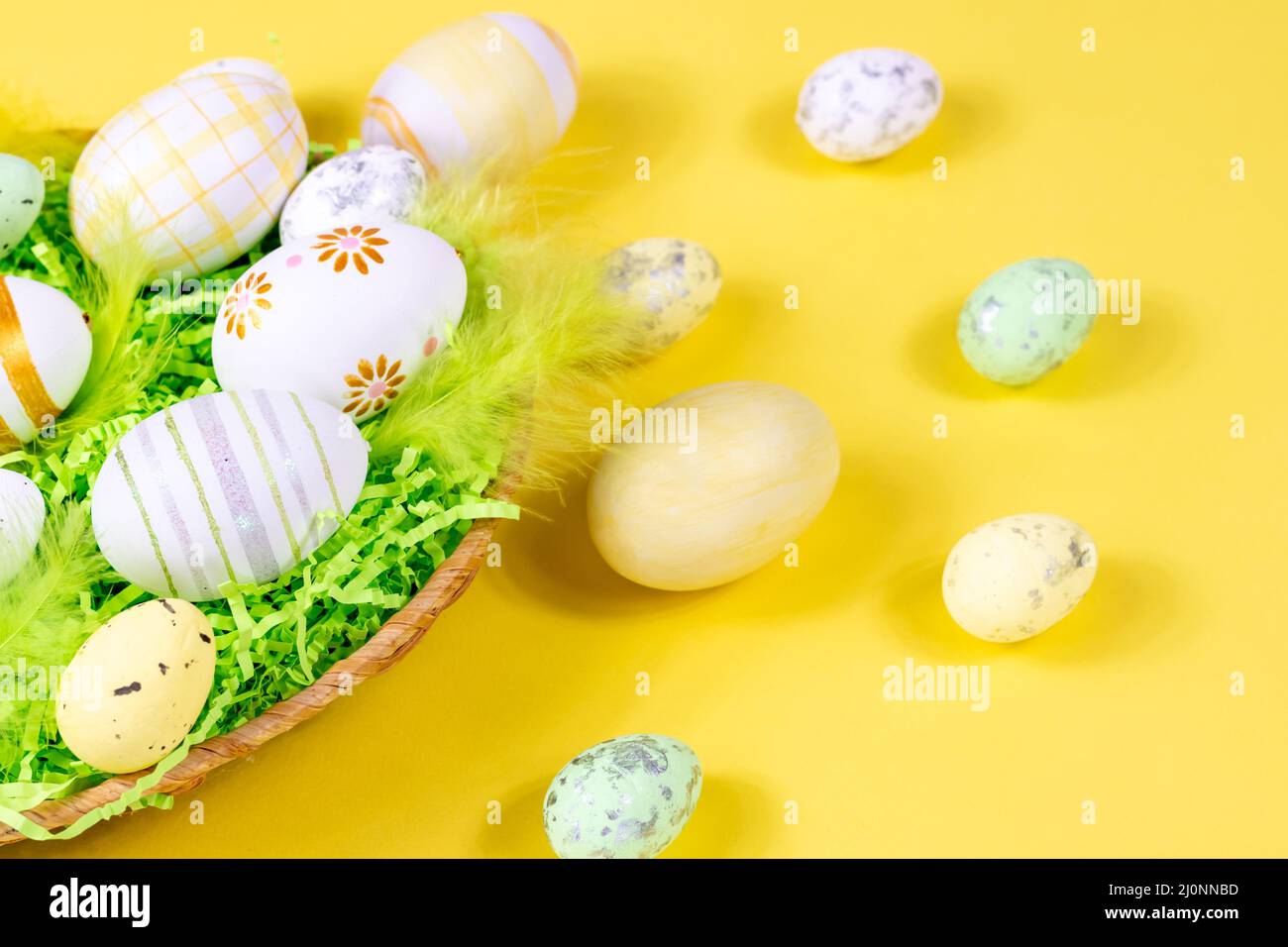 Les Pâques nichent avec des œufs et des plumes sur un fond jaune en gros plan. Concept minimal. Banque D'Images