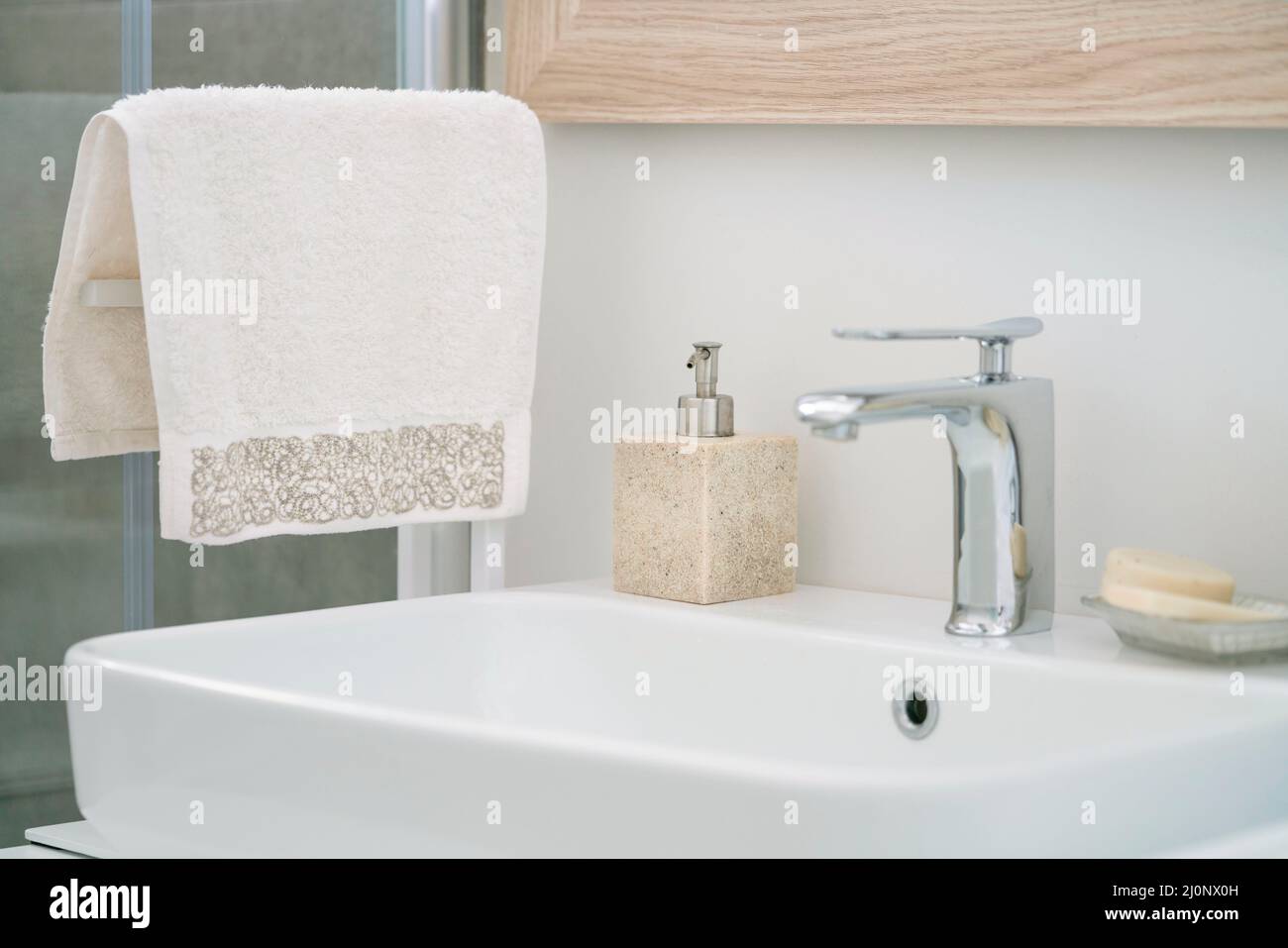 salle de bains, accent sélectif sur la serviette pendu et la bouteille de savon liquide par un lavabo blanc dans la salle de bains intérieure à la maison. robinets et savons sur blanc et c Banque D'Images