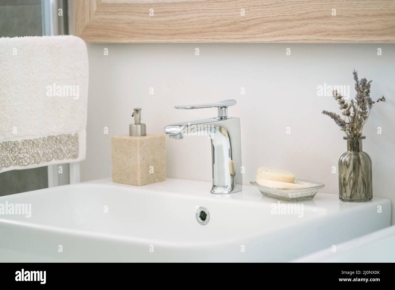 salle de bains, serviette pendue et bouteille de savon liquide par un lavabo blanc dans la salle de bains à l'intérieur de la maison. robinets et savons sur le lavabo blanc et propre dans le dôme Banque D'Images