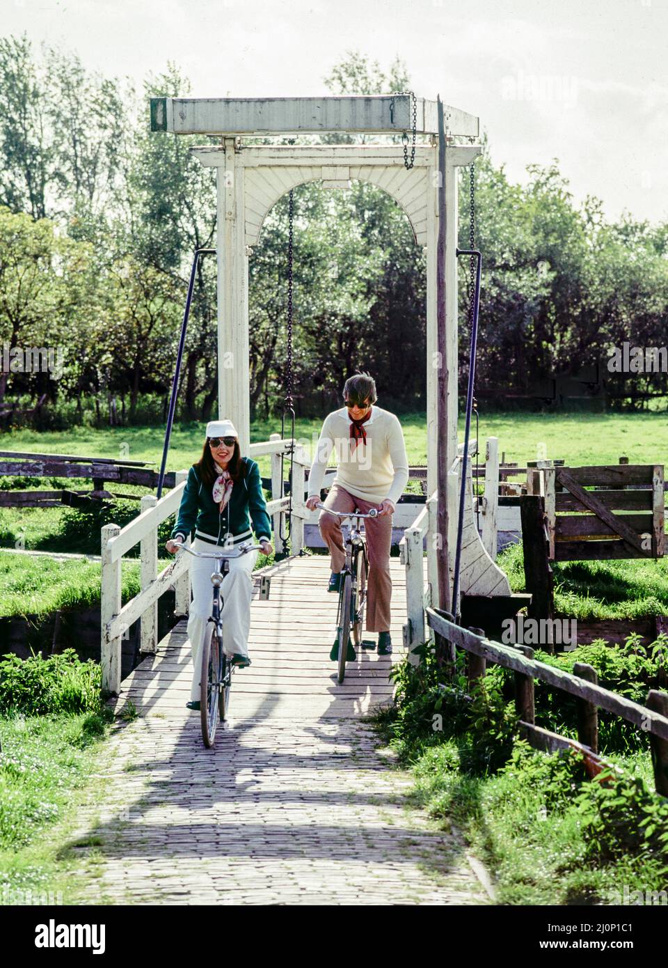 Vintage pays-Bas 1970s, couple de touristes d'âge moyen vélo, White drawbridge, Marken, Waterland, Nord de la Hollande, Pays-Bas, Europe, Banque D'Images